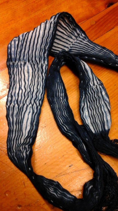 Knots cut on along one selvedge, opening the pleats.